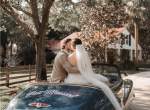 Wedding couple kissing on the back of a convertible with Just Married sign on it