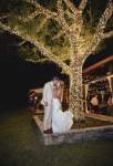 Wedding couple kissing under a tree with lights