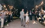 Bride and groom dancing down aisle of guests holding sparkles