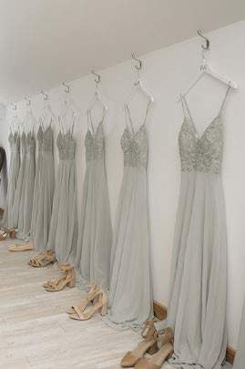 a row of wedding dresses hanging on a wall with shoes lined up in front of the dresses on the floor