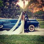a bride and groom standing in front of a classic Buick