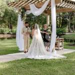 a bride and groom exchanging vows under a pergola